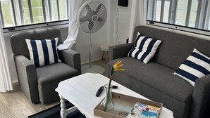A modern living room with a grey sofa, a white coffee table, and a grey armchair.