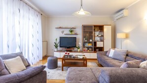 Un salon comprenant un canapé, une table basse, un téléviseur et une bibliothèque.