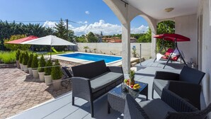 Un espace extérieur abrité comprenant une piscine, des meubles en osier et des plantes en pot.