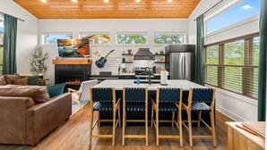 Een moderne keuken met een centraal eiland, houten plafond en grote ramen.
