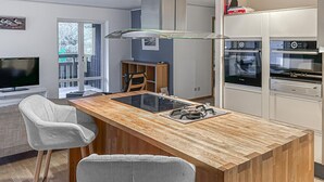 A modern kitchen with a central island, two bar stools, a built-in oven, and a large window. - Cozy home in åhus with sauna (Åhus)