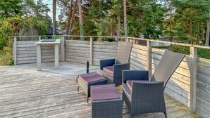 A wooden deck with wicker furniture, including chairs and a table. - Cozy home in åhus with sauna (Åhus)