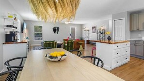A modern kitchen with white cabinets, a wooden countertop, and a hanging light fixture.