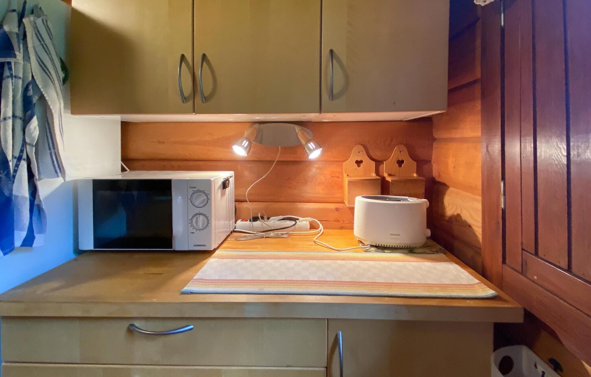 A kitchen with a microwave, toaster, and wooden cabinets.