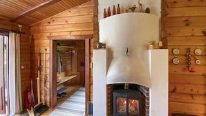 L’intérieur d’un chalet en bois, avec une cheminée, un escalier en bois et divers ustensiles de cuisine accrochés au mur.