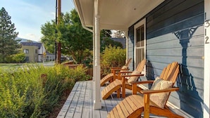 A wooden deck with outdoor furniture, a house with a dark blue exterior, and a number '312' on the wall.