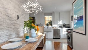 A modern kitchen with white cabinets, a wooden countertop, and a stainless steel oven.