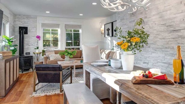 A modern living room with a fireplace, a dining area with a wooden table, and a kitchen area with a stove.