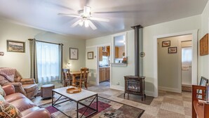 A living room with a sofa, coffee table, and fireplace. There is a dining area with a table and chairs, and a kitchen in the background. - Papa's Cottage- Dog Friendly- Close to Monarch (Salida)