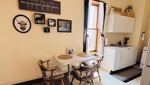 A compact kitchen with a dining table, chairs, and a refrigerator.
