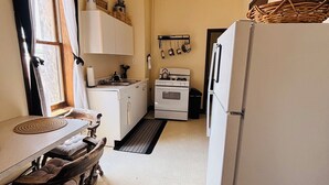 A compact kitchen with a white refrigerator, stove, and ceiling fan.