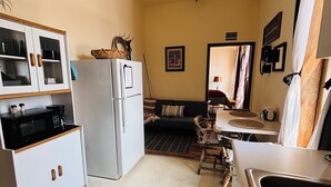 A compact kitchen with a refrigerator, microwave, and cabinets. There is a dining area with a table and chairs, and a sofa.