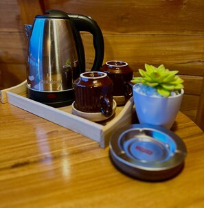 A wooden table with a stainless steel kettle, two ceramic mugs, a small potted plant, and a tray. - MR GLAMPING & VILLA (Bedugul)