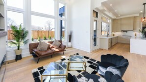 A spacious living area with a leather sofa, a glass coffee table, and a black and white rug. - Luxury 5 BR, Gym, Sauna, Thtr, OD FP & Ktcn, Lake (Burlington)
