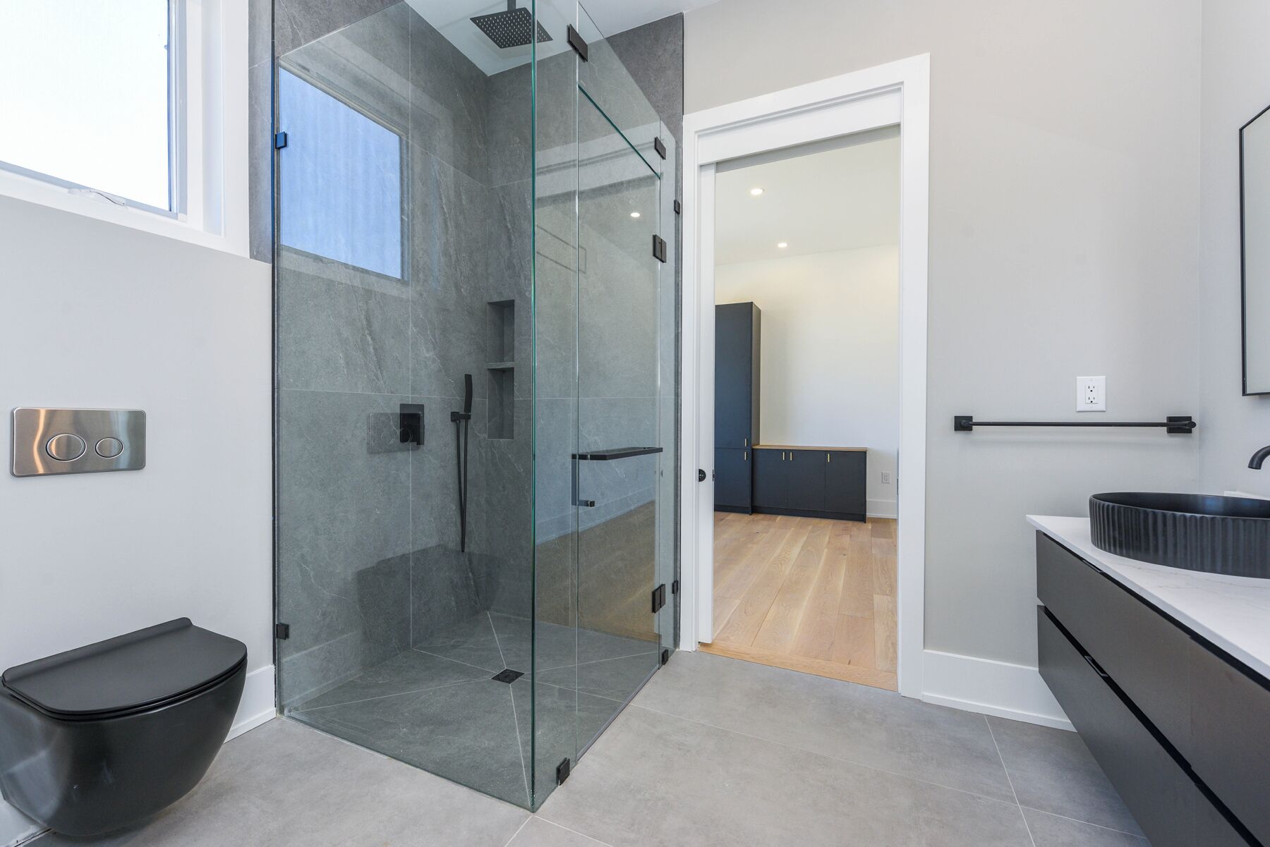A modern bathroom with a glass-enclosed shower, a toilet, and a vanity with a sink.