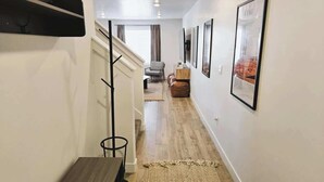 A hallway with a staircase, a dining table, and framed pictures on the walls.