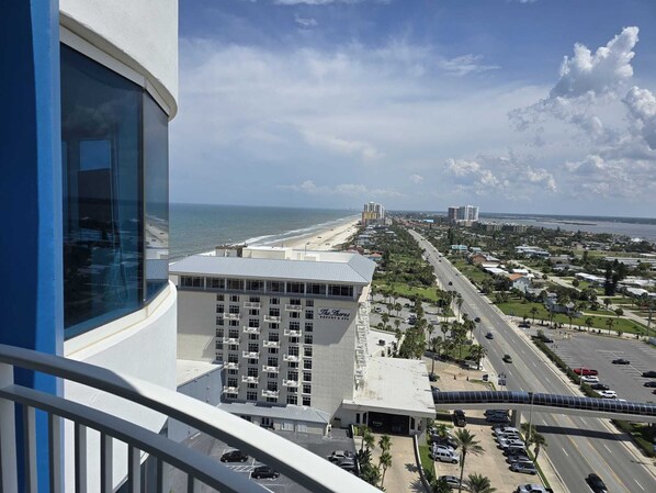 Hotel com vista para a praia, estacionamento e uma estrada com carros.