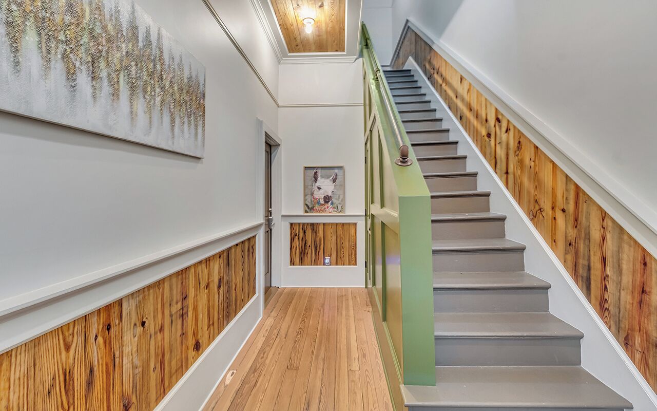 A staircase with wooden paneling on the walls and a green handrail.