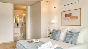A modern hotel room with a neatly made bed, a bedside table with a lamp, and a framed artwork on the wall. - Balcony 2BRs with Pool & Parking by HostWise (Vila Nova de Gaia)