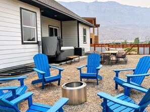 A patio area with blue Adirondack chairs, a fire pit, and a table with chairs. - NEW! GameRm–HotTub–TheaterRm–Mtn Views–3000sf–BBQ (Spanish Valley)