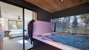 A modern bathroom with a glass-enclosed hot tub, a wooden ceiling, and a view of a bedroom with a bed and a ceiling fan. - Newly Built/Furnished Quiet Lux Ski-In/Out Hot Tub (Government Camp)