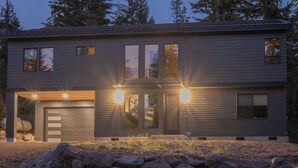 A modern two-story house with a garage, large windows, and a well-lit entrance. - Newly Built/Furnished Quiet Lux Ski-In/Out Hot Tub (Government Camp)