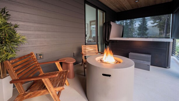 A modern outdoor seating area with a fire pit, wooden chairs, and a television screen. - Newly Built/Furnished Quiet Lux Ski-In/Out Hot Tub (Government Camp)