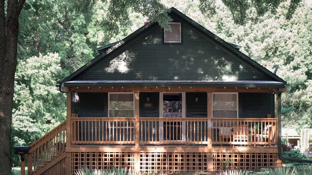 A cabin with a wooden deck, a covered porch, and a large window overlooking a forested area. - Perfect Group Stay! See the Stunning Social Area X6 (Grandview)