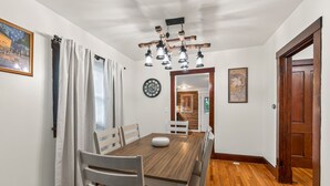 A dining room with a wooden table, white chairs, a clock, and a chandelier. - Perfect Group Stay! See the Stunning Social Area X6 (Grandview)