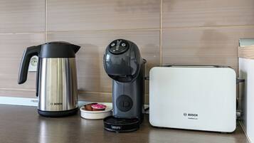 Una cucina con una macchina da caffè Bosch, un bollitore e un tostapane sul piano di lavoro.