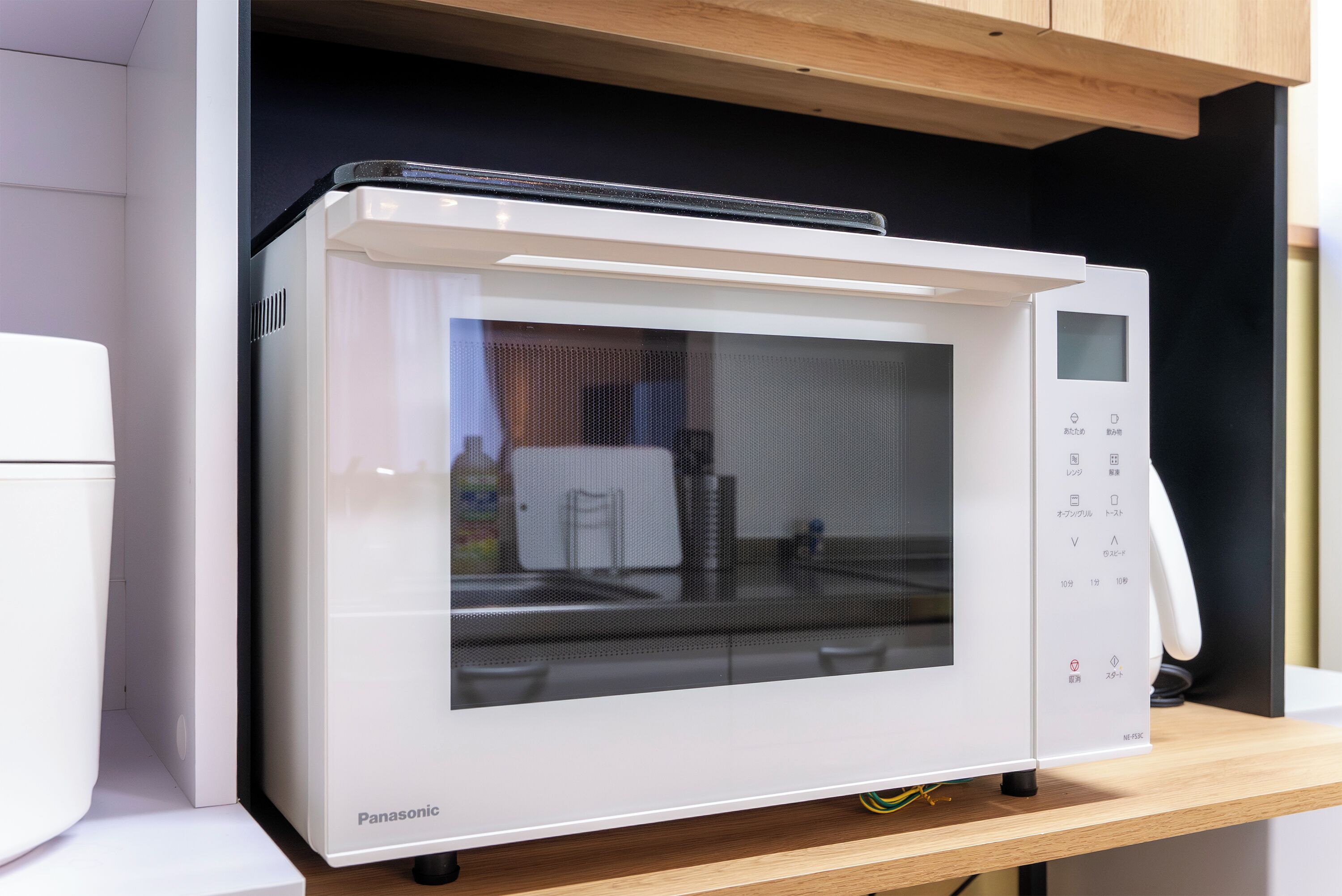 A Panasonic microwave oven with a digital display and control panel, placed on a wooden countertop.