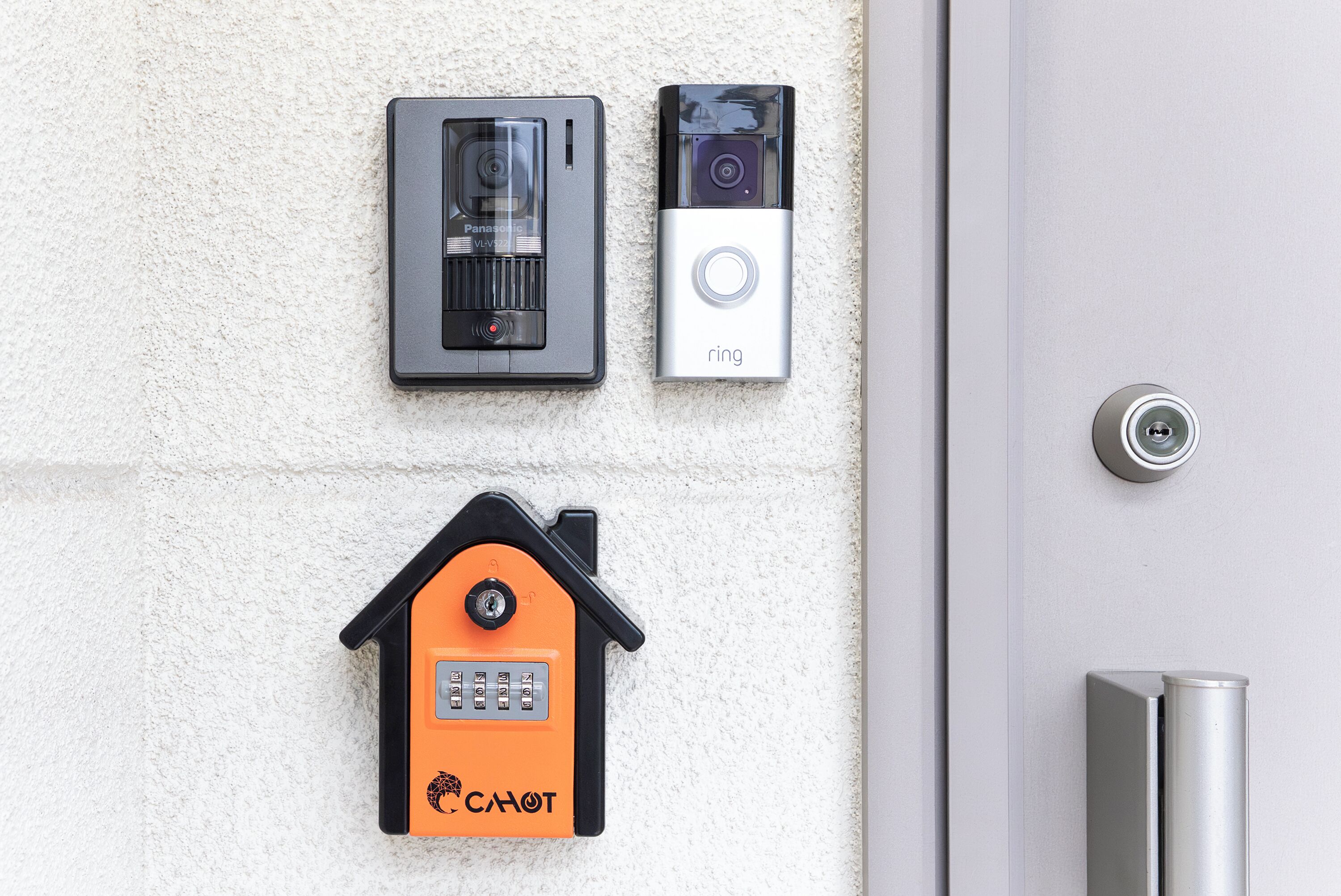 A door with a key lock, a wall-mounted intercom system, and a doorbell.
