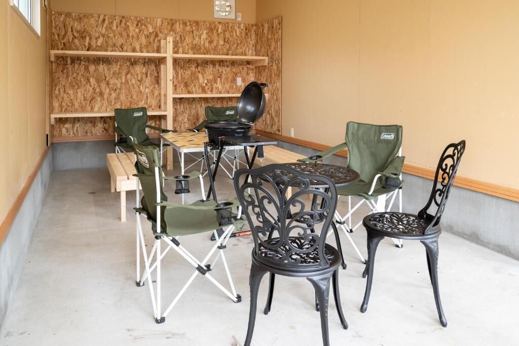 A dining area with a round table, four chairs, and a portable grill.