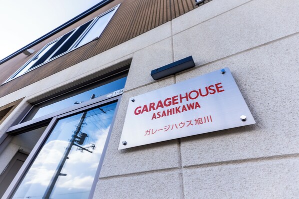 Un bâtiment sur lequel est apposée une enseigne indiquant « GARAGEHOUSE ASAHIKAWA » et qui comporte également du texte en japonais.