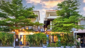 A modern hotel with a balcony, surrounded by lush greenery and a well-lit entrance. - 6BRs w/ Private Pool & Billiard - 7min to Beach (Thành phố Hội An)