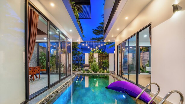 A modern indoor swimming pool with glass walls, a clear water surface, and a purple lounge chair. - 6BRs w/ Private Pool & Billiard - 7min to Beach (Thành phố Hội An)