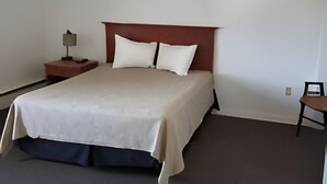 Une chambre à coucher avec un lit, une table de chevet, une chaise et une lampe.
