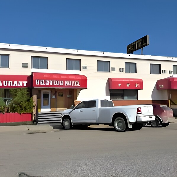 A white pickup truck parked in front of a building with red awnings and a sign above.