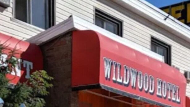 Un hôtel Wildwood avec un auvent rouge et deux motos garées devant.