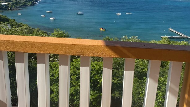 A balcony with a view of the sea, boats, and distant islands. - Marvelous 2-bedroom apartment with AC (Grenadines)