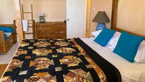 A bedroom with a bed, a wooden dresser, a nightstand, a lamp, and a door leading to another room. - Marvelous 2-bedroom apartment with AC (Grenadines)