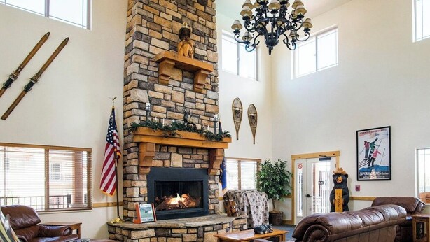 Un salón amplio con chimenea de piedra, mobiliario de cuero y un ventanal grande.