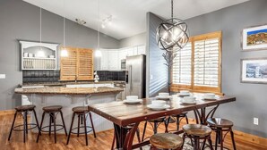 Una cocina moderna con una isla central, taburetes de bar y una mesa de comedor preparada para seis comensales.