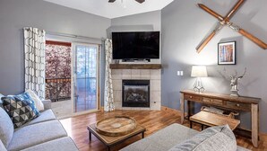 Una sala de estar moderna con chimenea, televisión y ventilador de techo.
