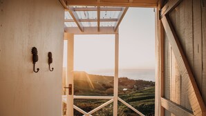 Una scala in legno conduce a un balcone con vista su un paesaggio pittoresco, colline e un lago.