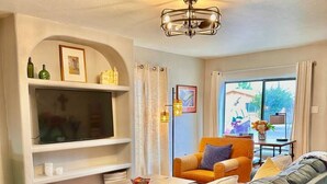 Una sala de estar con un sofá, sillones, una mesita de centro, un televisor y una lámpara de techo.