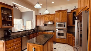 A spacious kitchen with wooden cabinets, granite countertops, stainless steel appliances, and a central island.