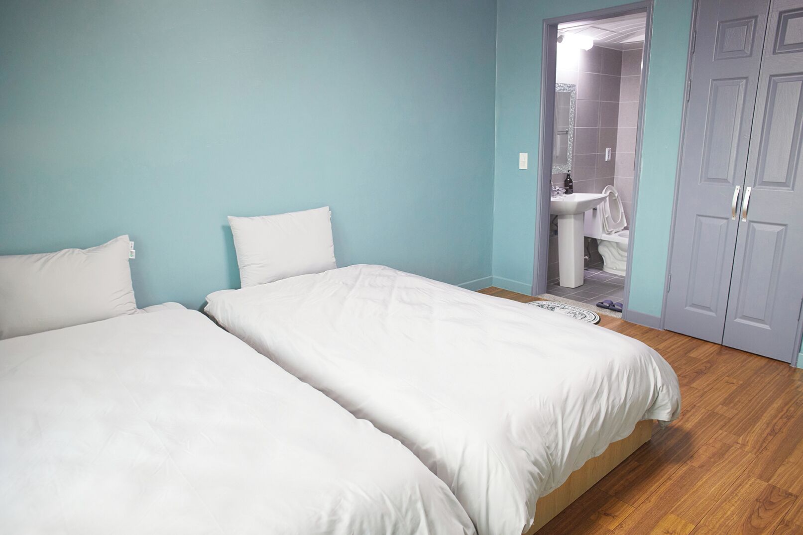 A bedroom with two beds, a bathroom with a sink, and a wardrobe.