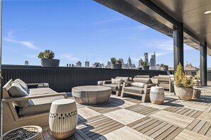 A rooftop terrace with outdoor seating, potted plants, and a city skyline view. - Boutique Studio with Rooftop View and Gym (Philadelphia)