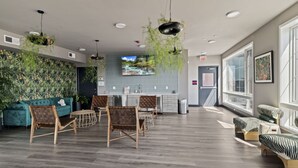 A modern reception area with a sofa, chairs, a counter, and a large window. - Boutique Studio with Rooftop View and Gym (Philadelphia)